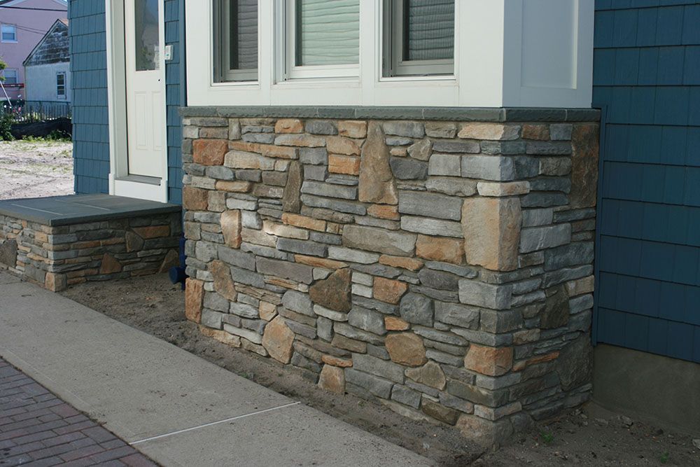 A blue house with a stone wall and a window