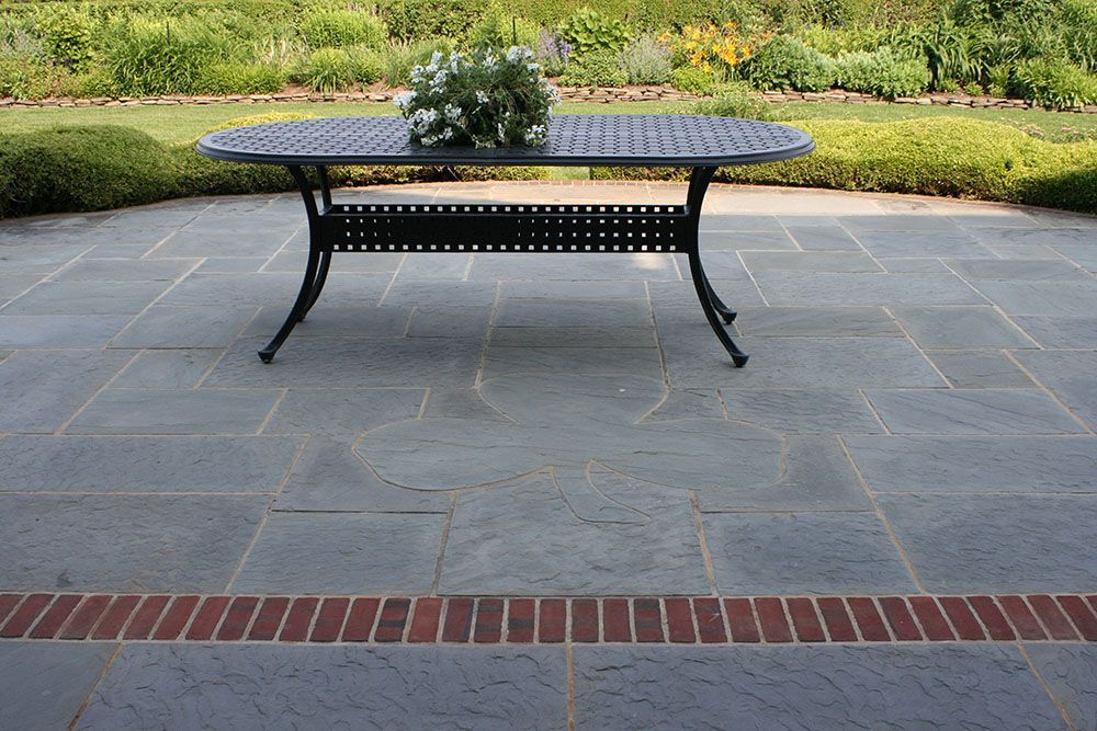 A table on a patio with a vase of flowers on top