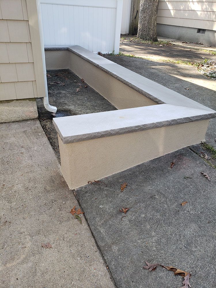 A concrete bench is sitting on the sidewalk next to a house