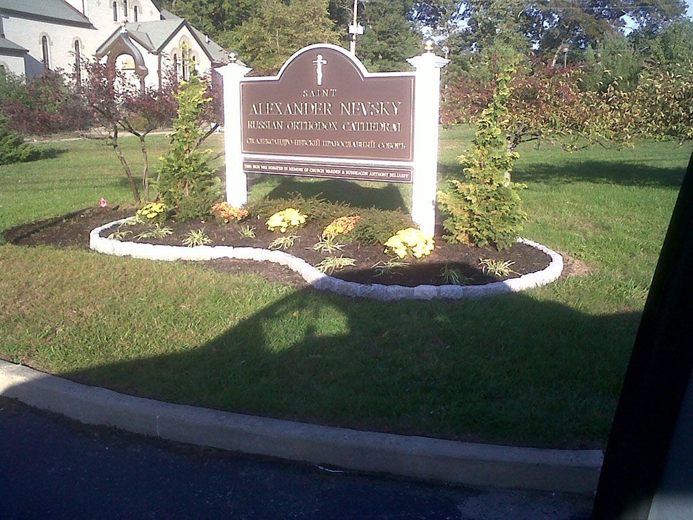 A sign for a church is in the middle of a lush green field