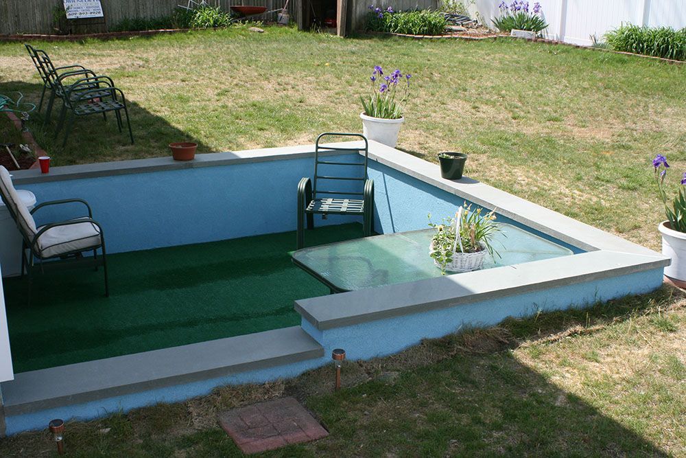 A swimming pool in a backyard with chairs and flowers