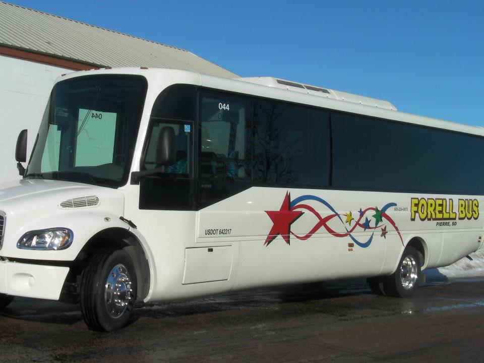 A white forell bus is parked in front of a building