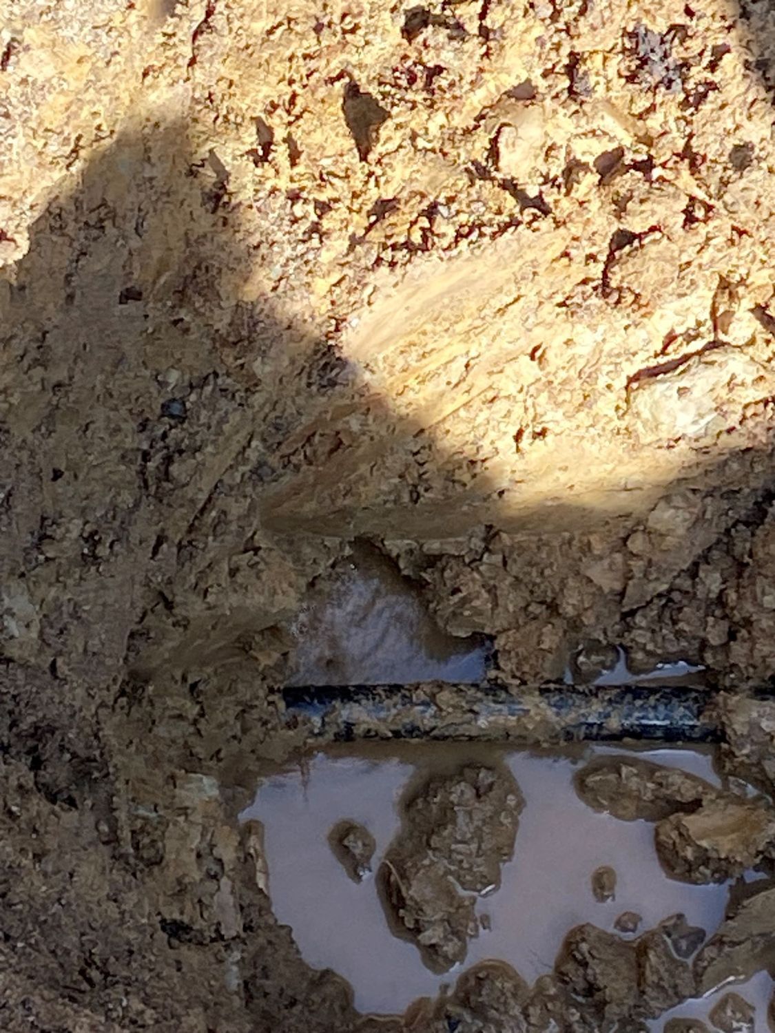 A puddle of water is coming out of a hole in the ground.