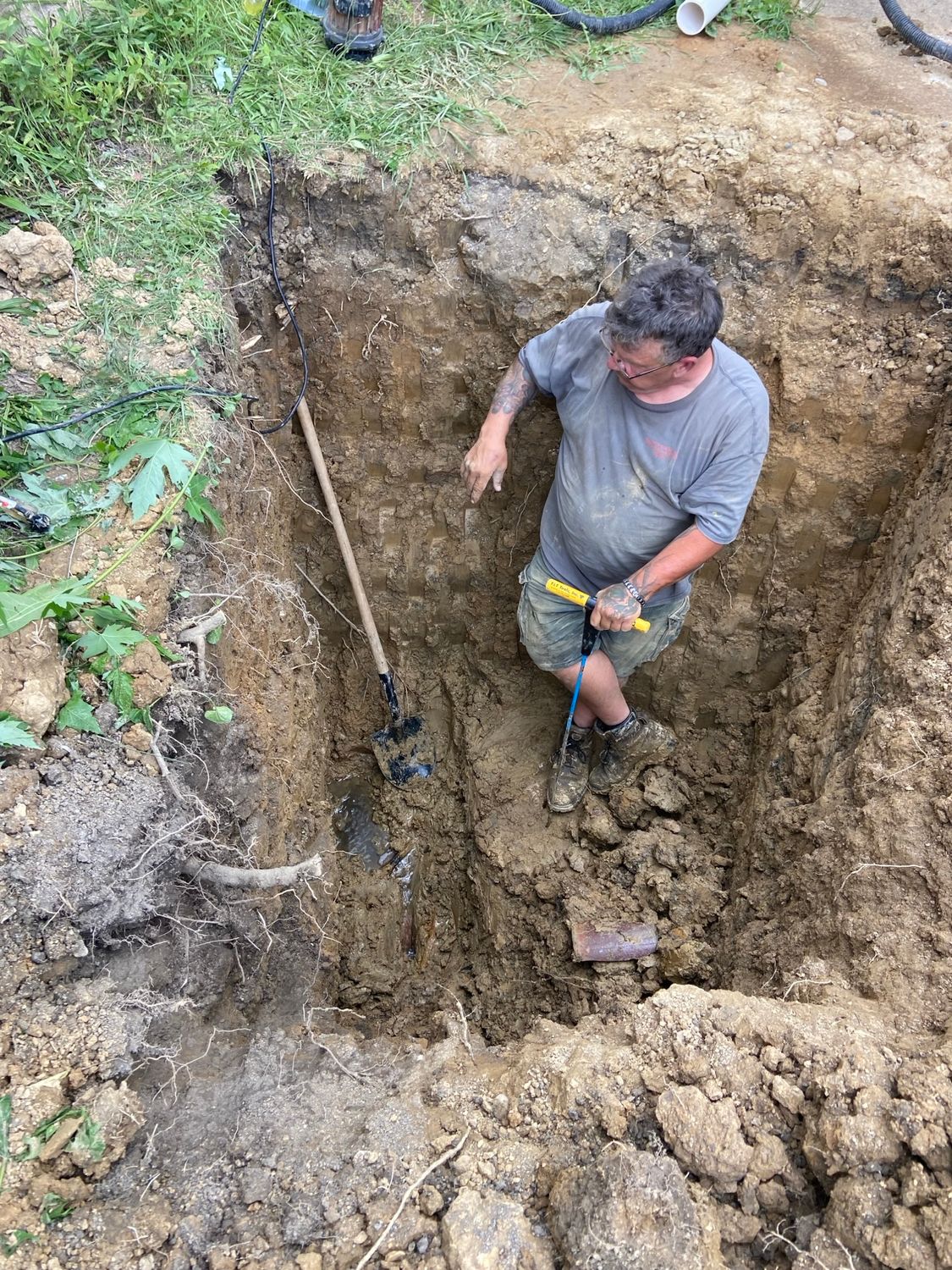 A man is digging a hole in the dirt with a shovel.