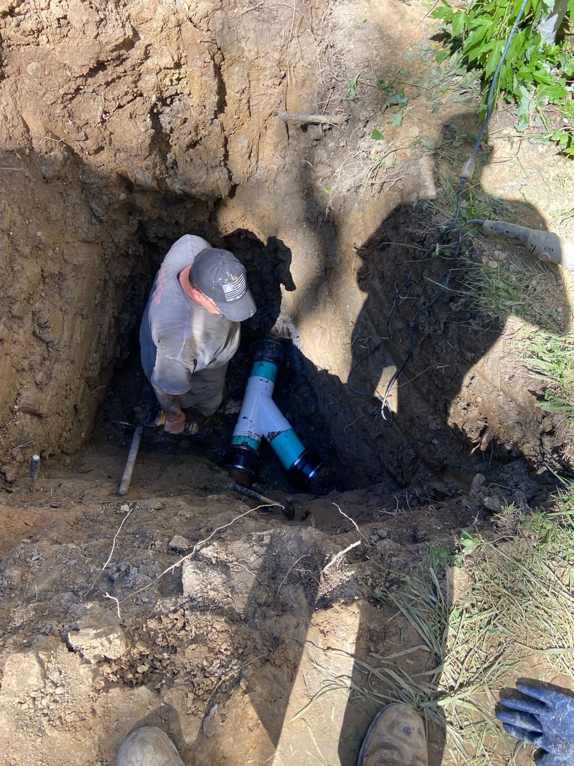 A man is working on a pipe in the dirt.