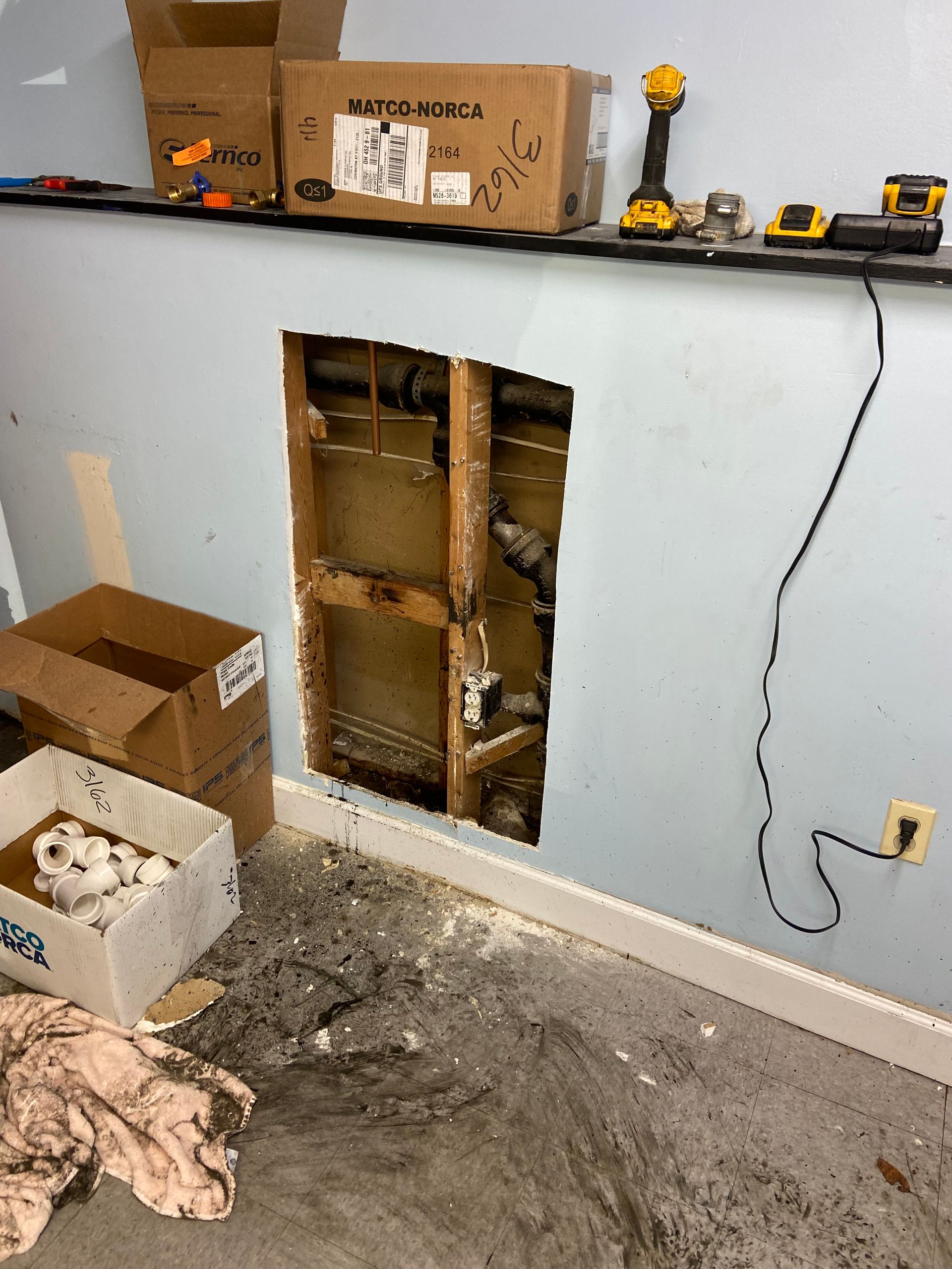 A room with a hole in the wall and boxes on the floor.