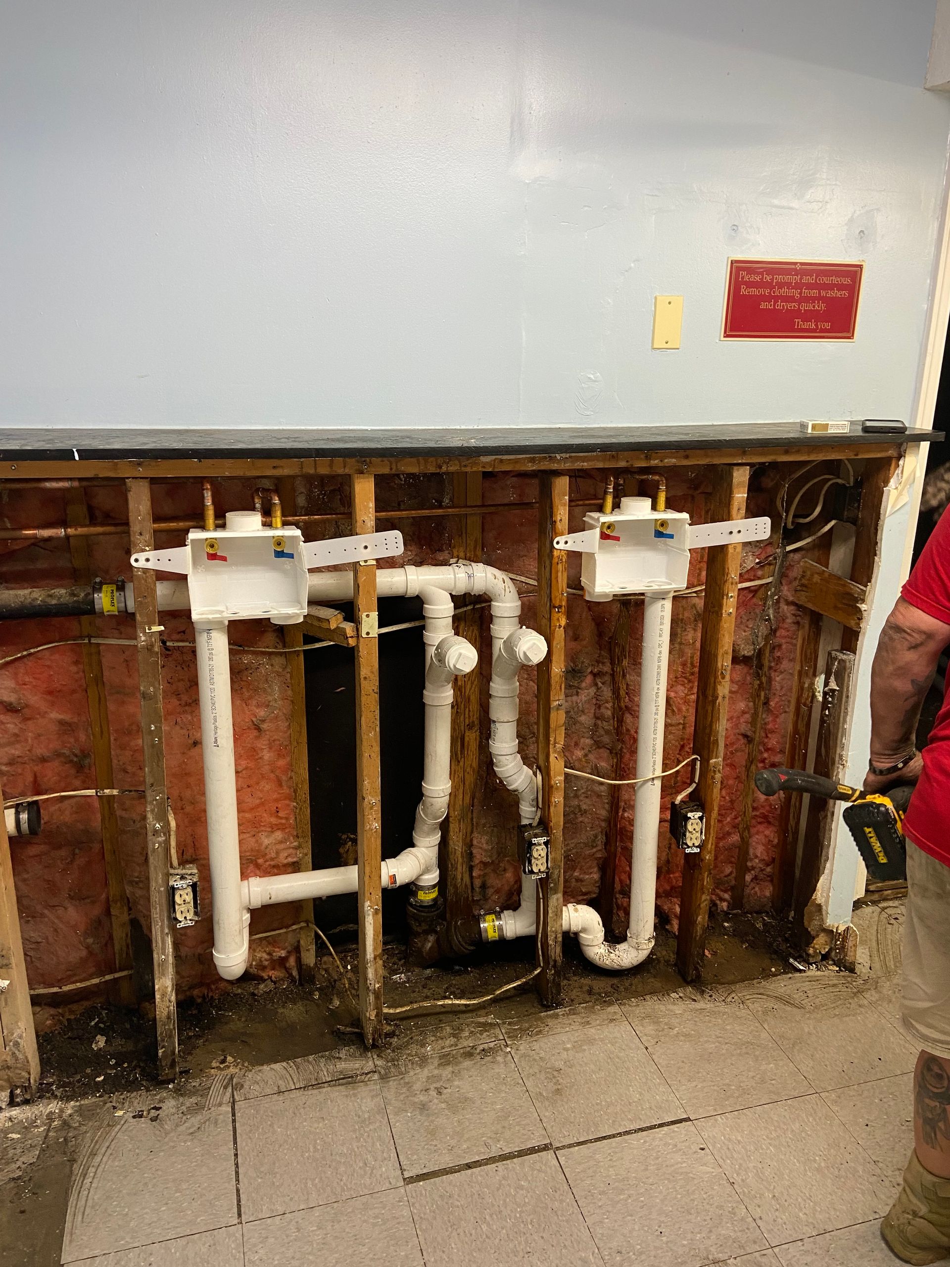 A man is standing in front of a wall with pipes coming out of it.