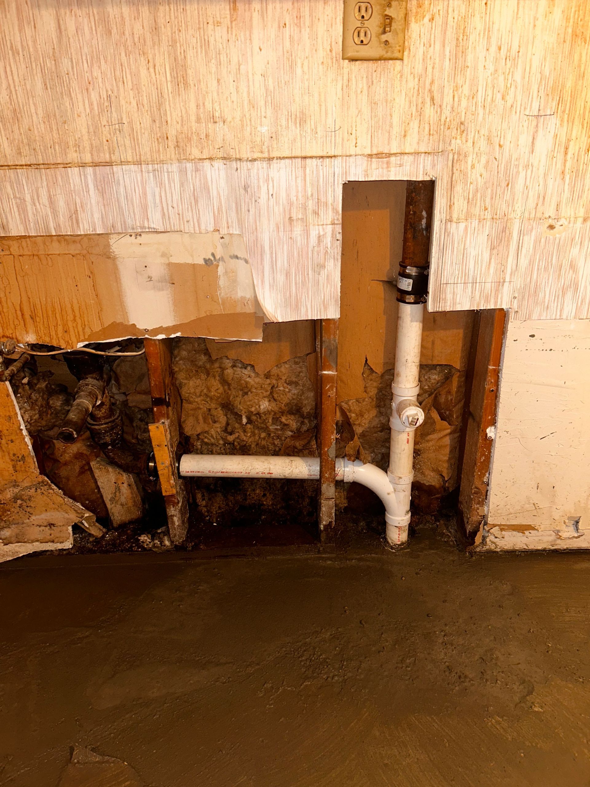 A white pipe is coming out of a hole in a wall.