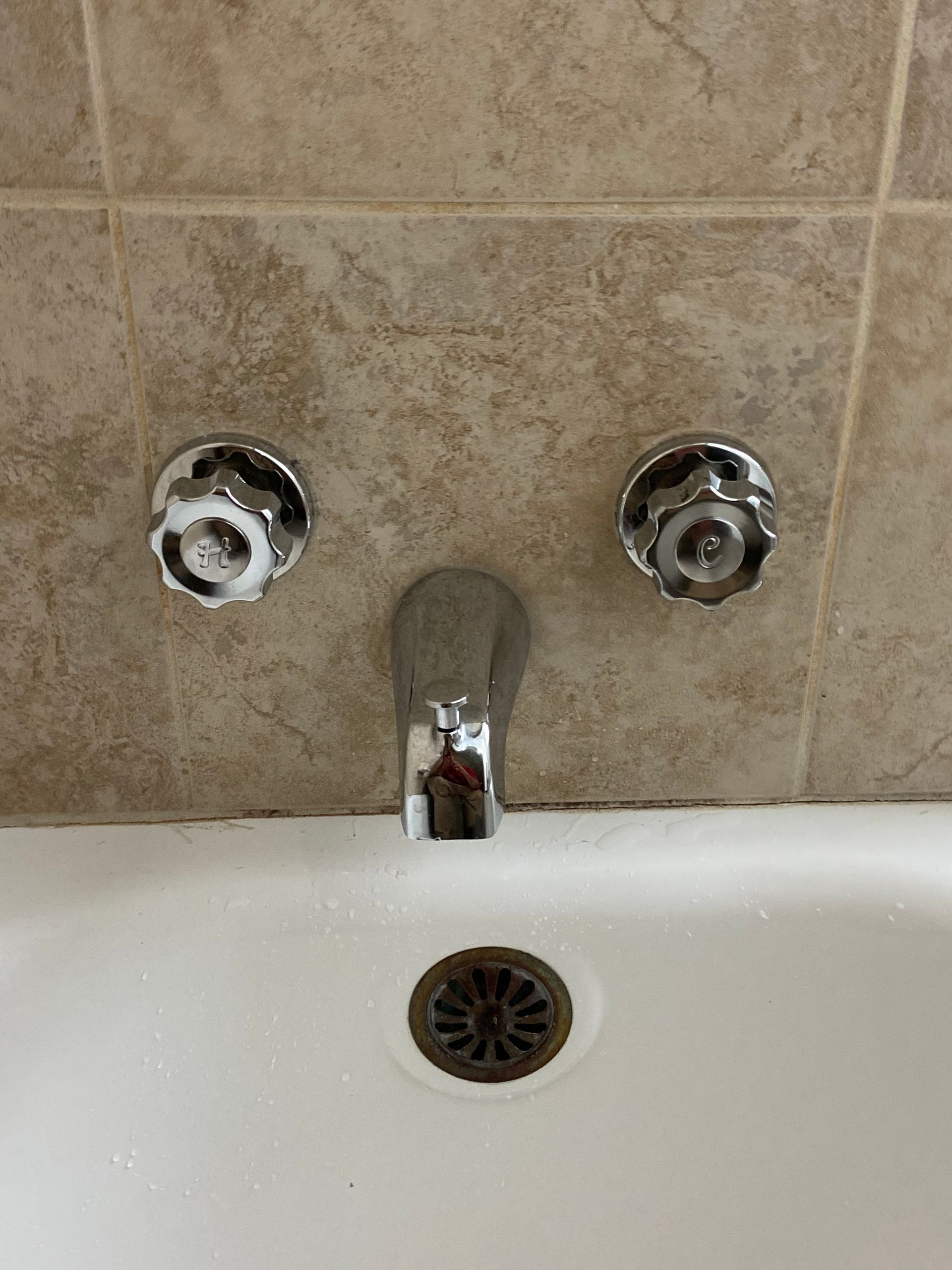 A close up of a bathtub with a faucet and drain.