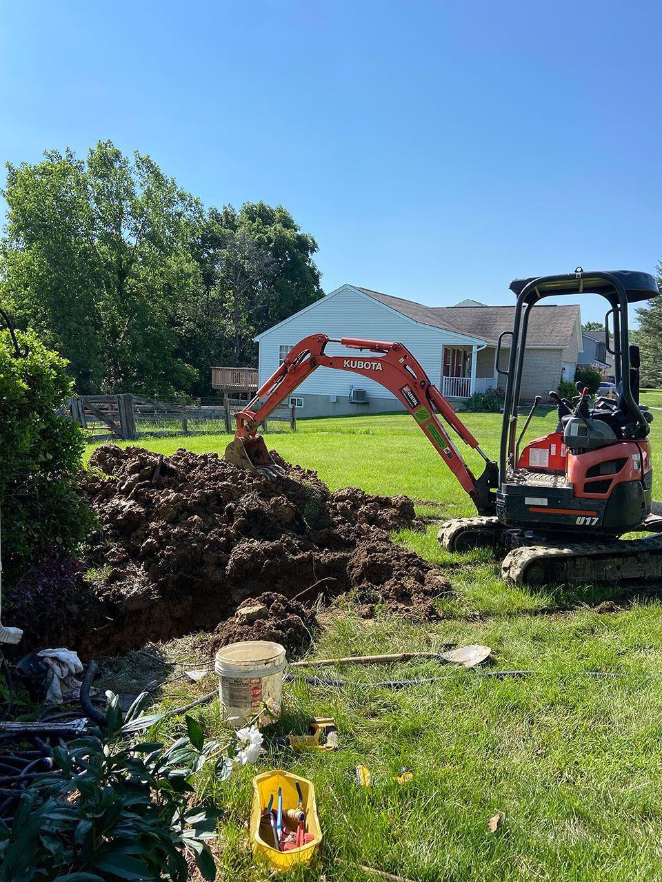 A small excavator is digging a hole in a yard