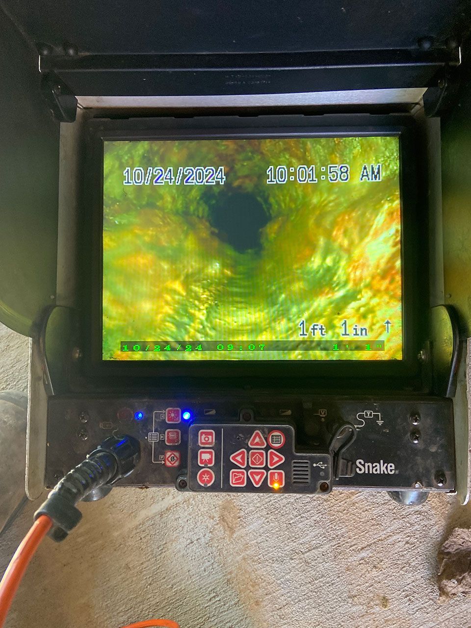 A snake camera is sitting on a carpeted floor