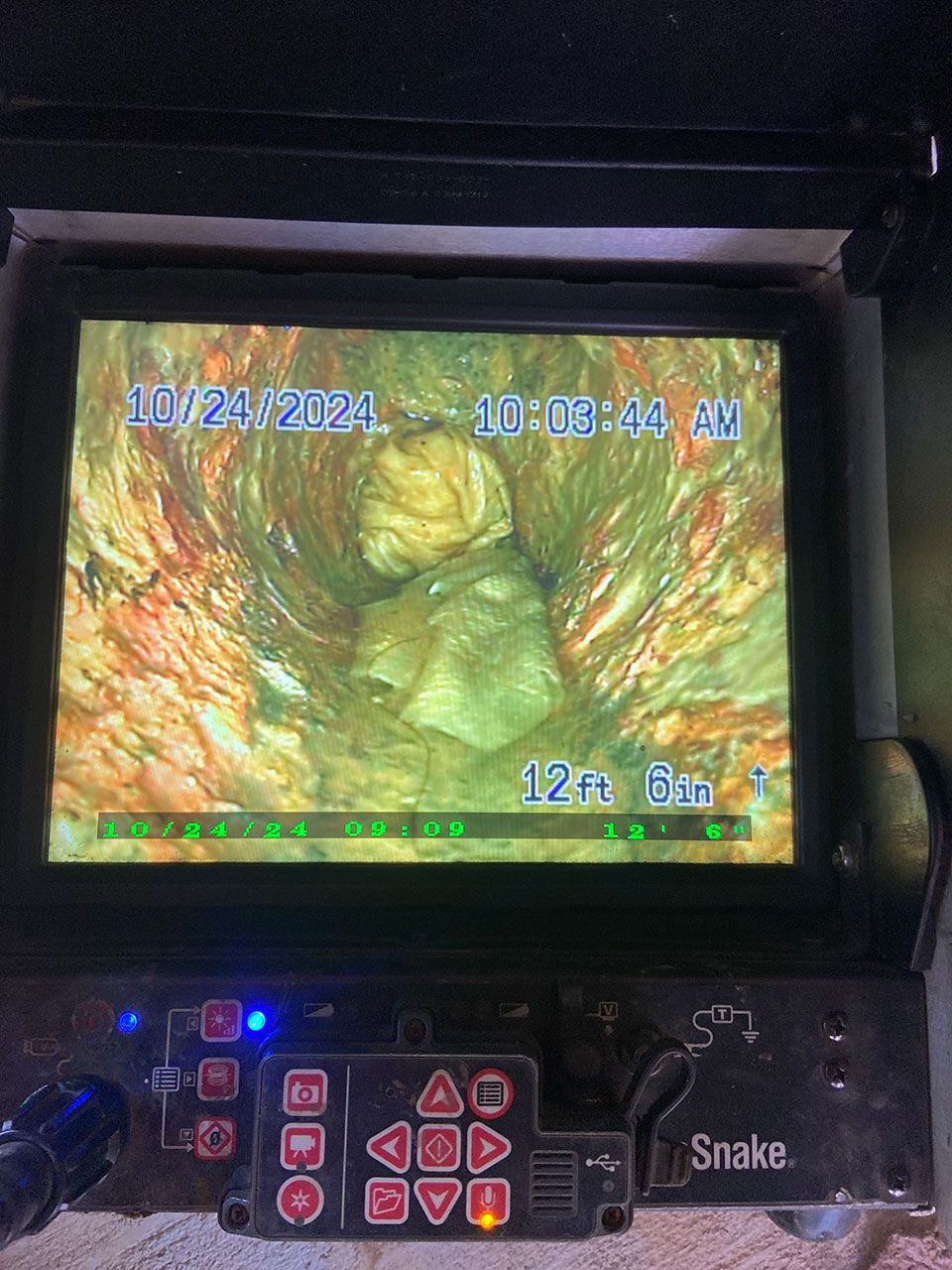 A camera is taking a picture of a snake in a drain