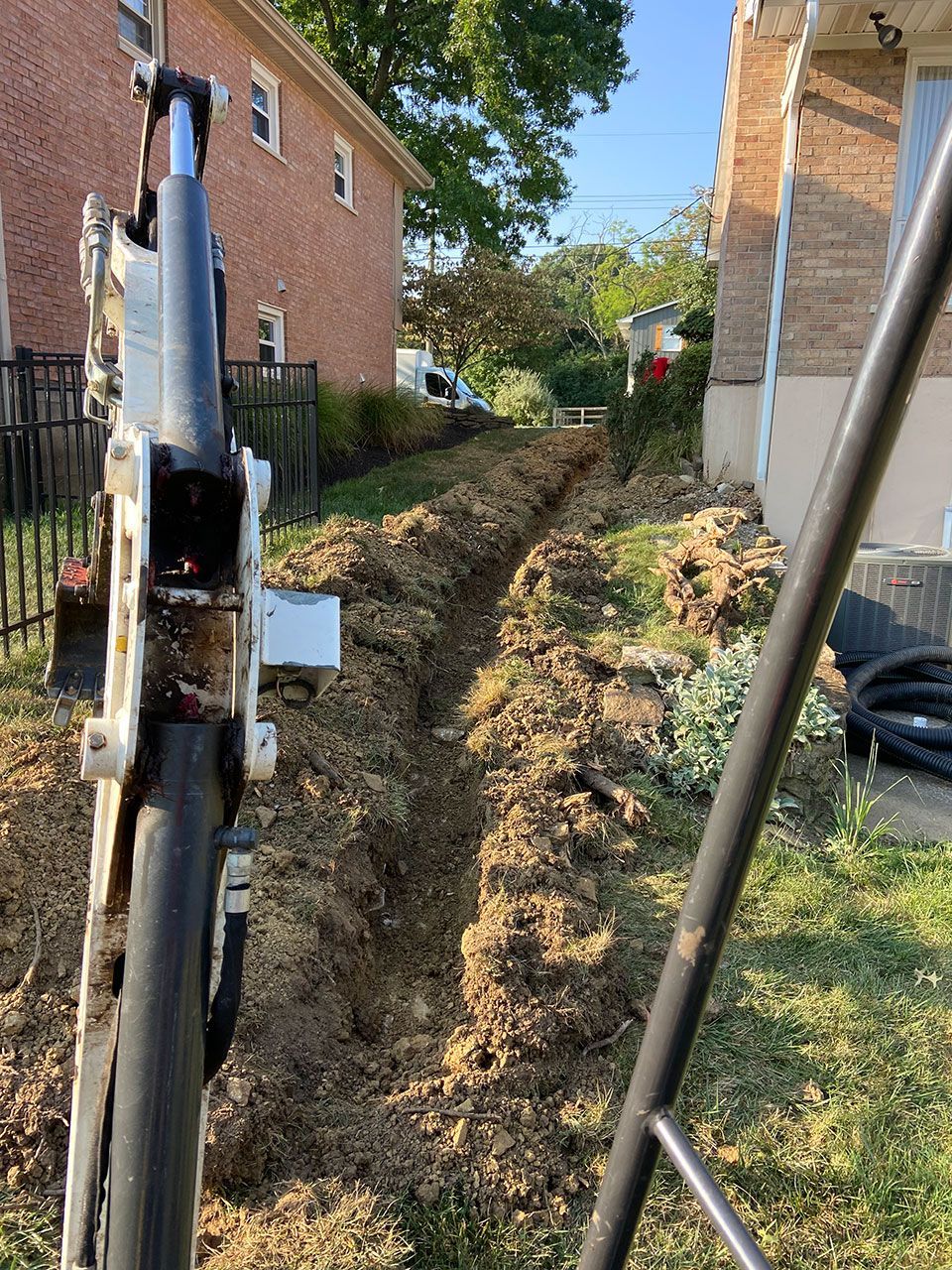 A machine is digging a hole in the ground in front of a house