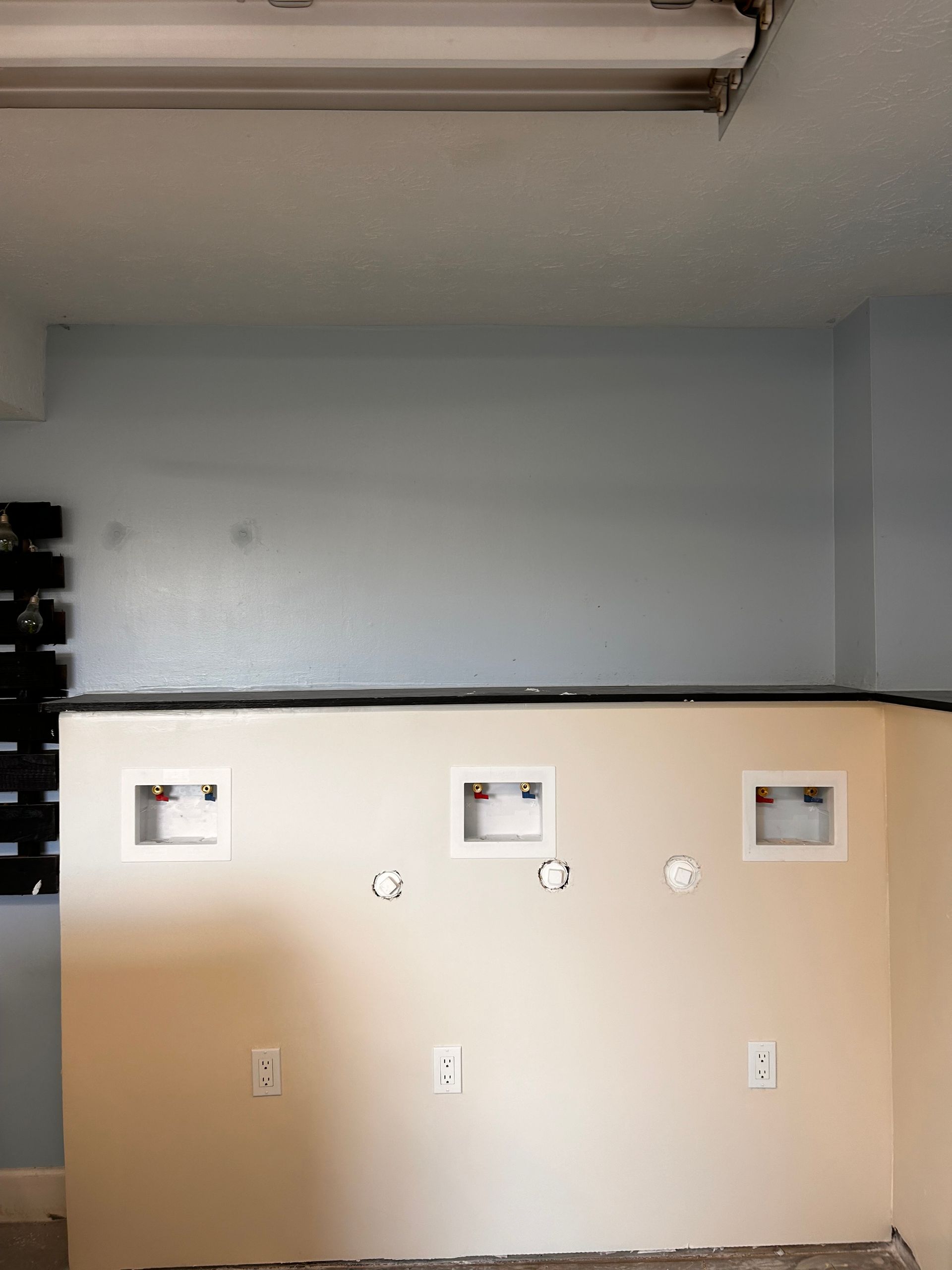 An empty room with a white wall and a light on the ceiling.