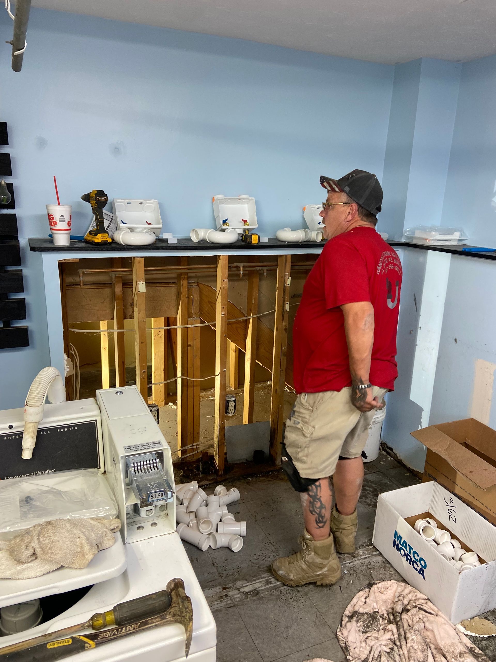 A man in a red shirt is standing in a room.
