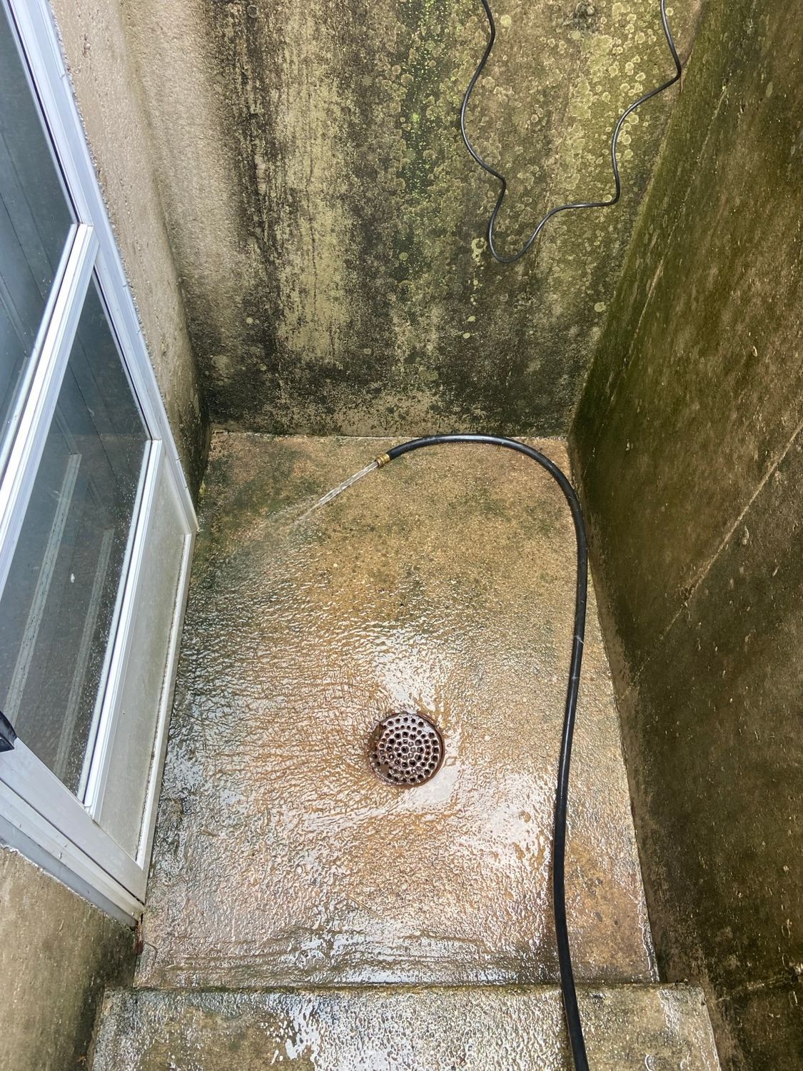 A hose is spraying water on a concrete floor next to a door