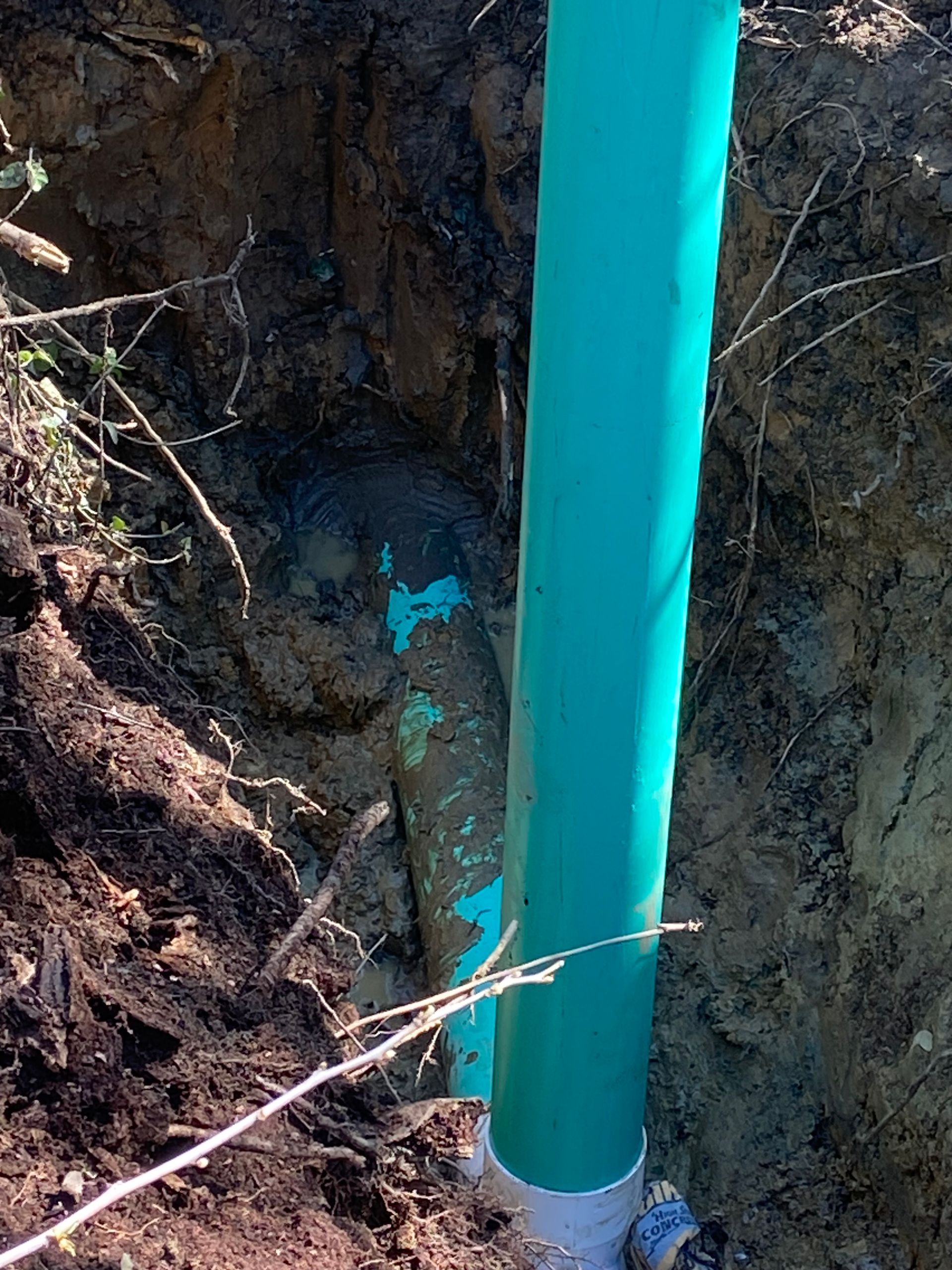 A green pipe is sitting in the dirt in a hole