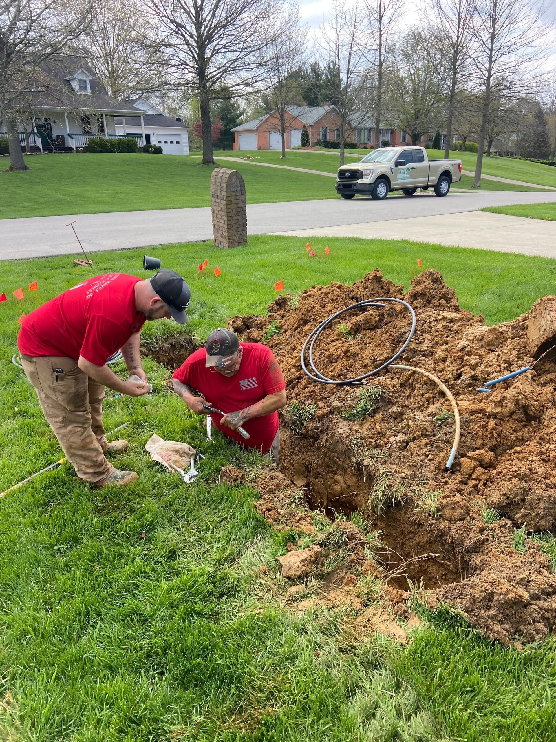 Two men are digging a hole in the ground in a yard