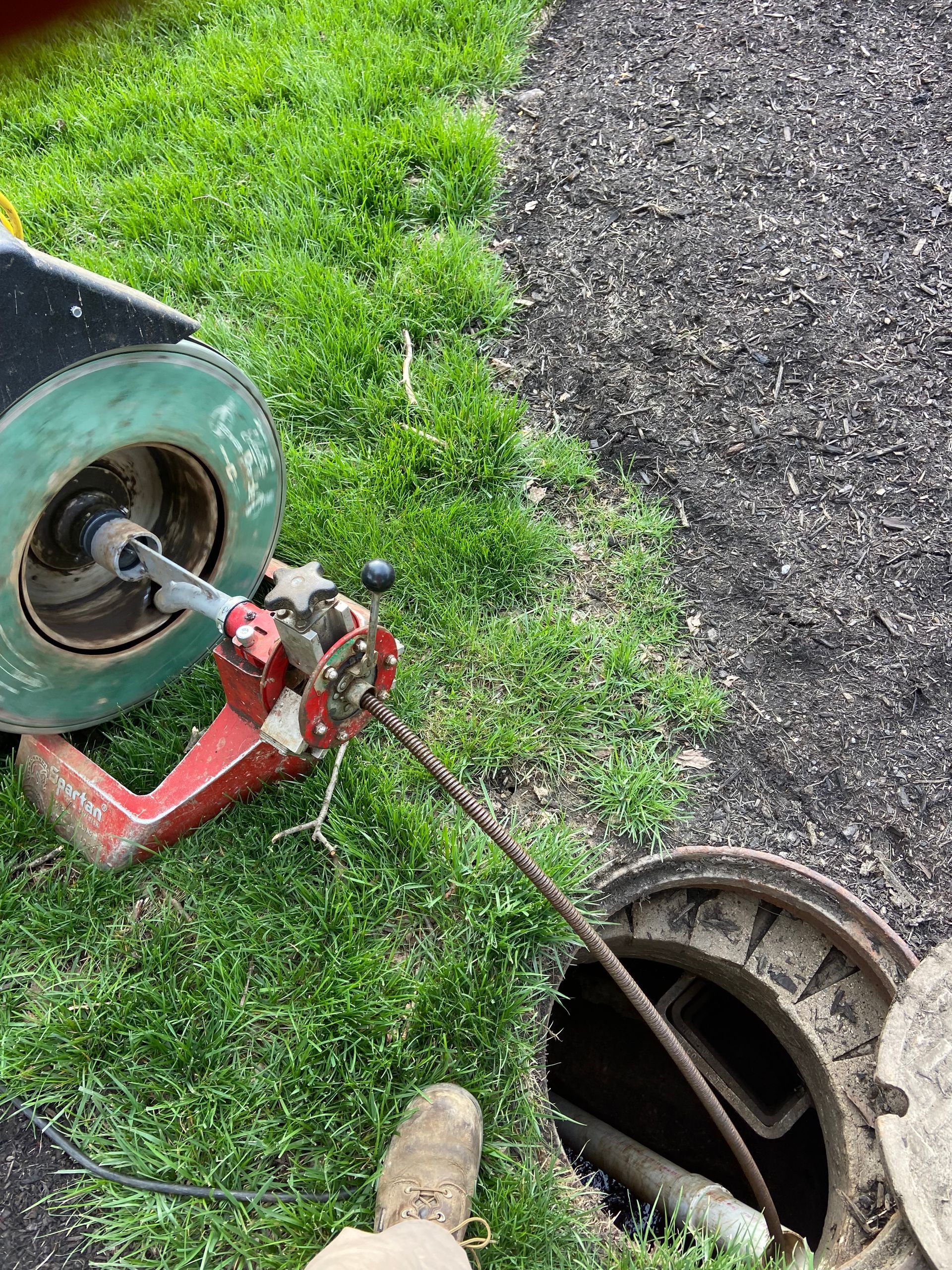 A manhole cover is being opened by a drain cleaner