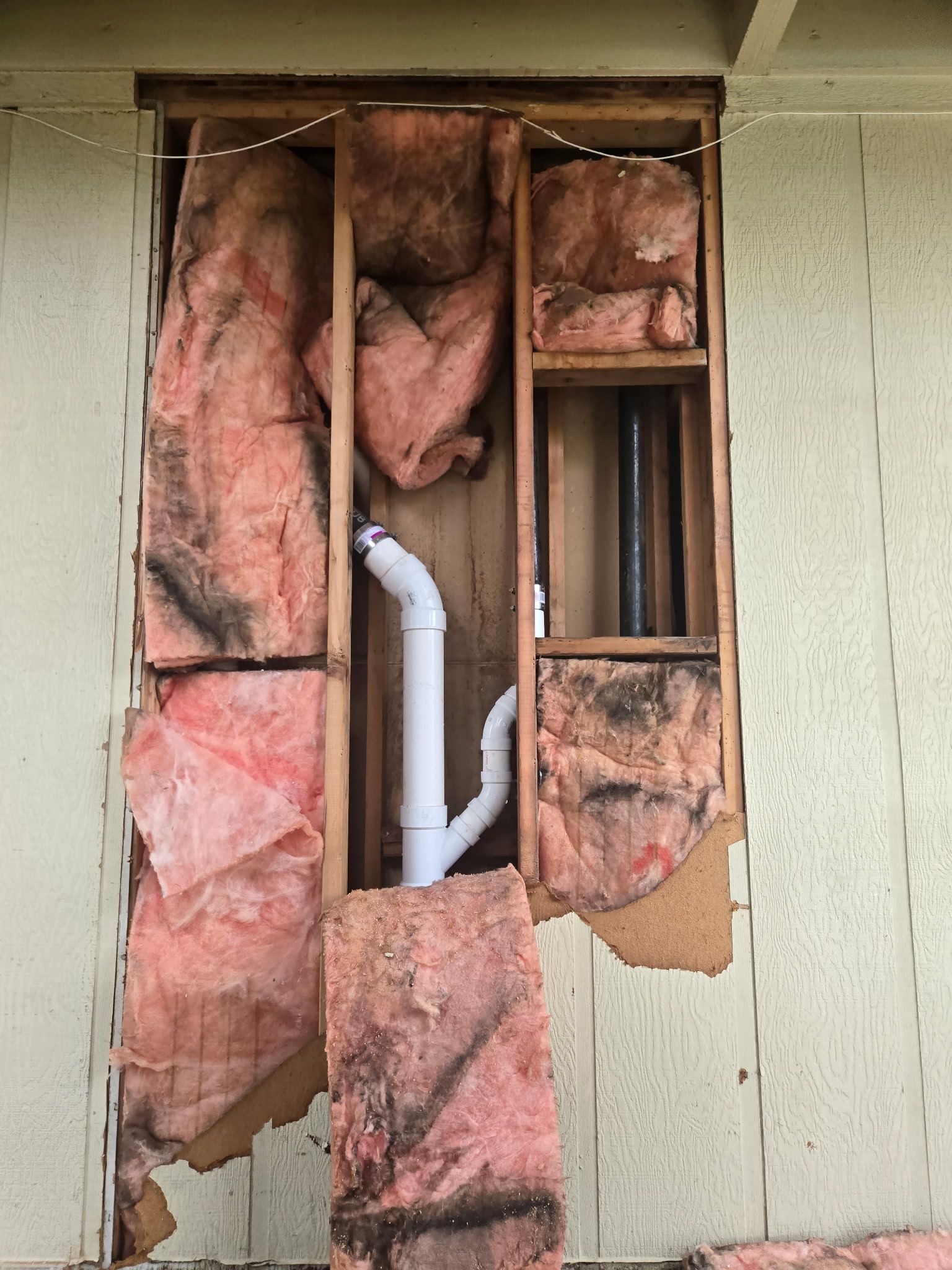 A pipe is coming out of a hole in a wall