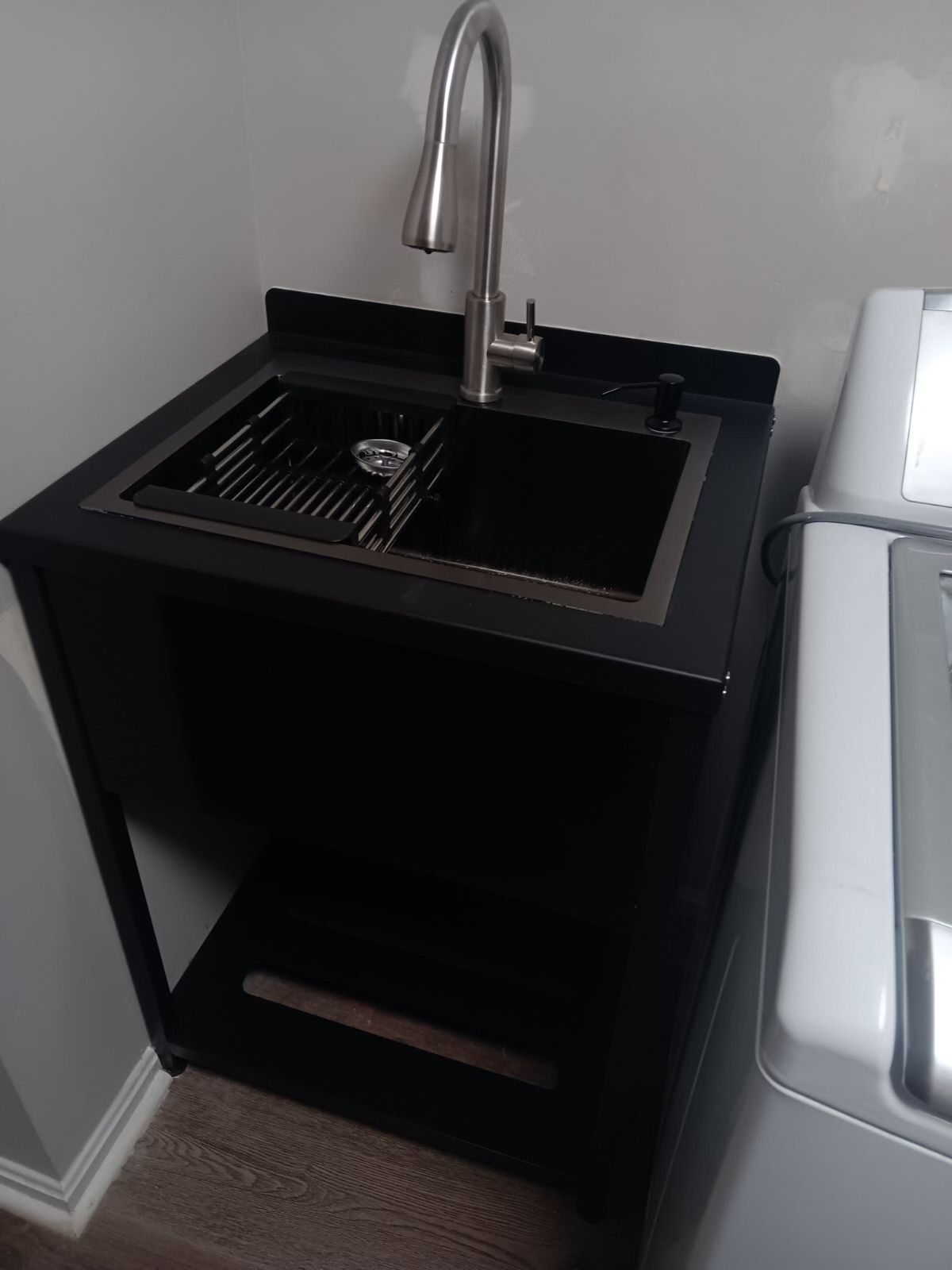 A black sink is sitting next to a washing machine in a laundry room.