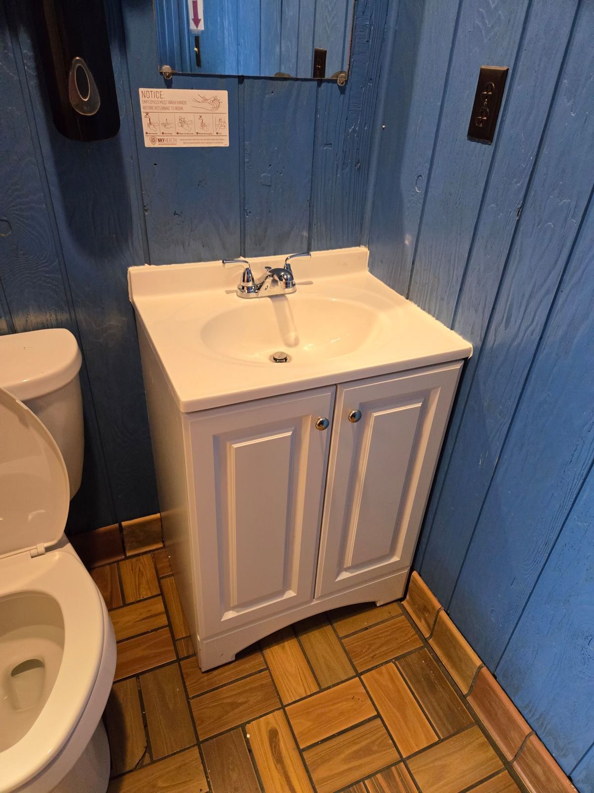 A bathroom with a toilet , sink and mirror.