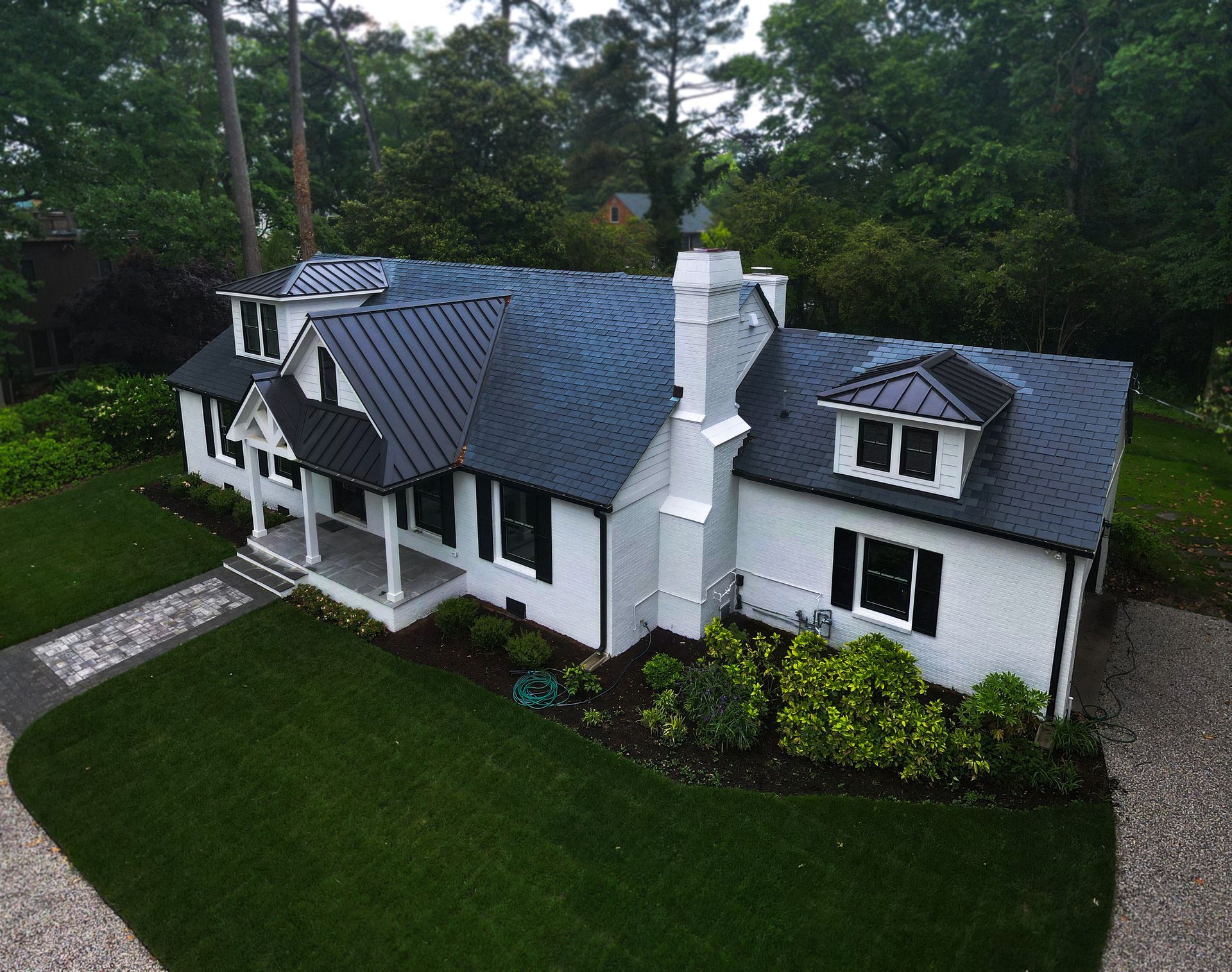 An aerial view of a white house with a black roof.