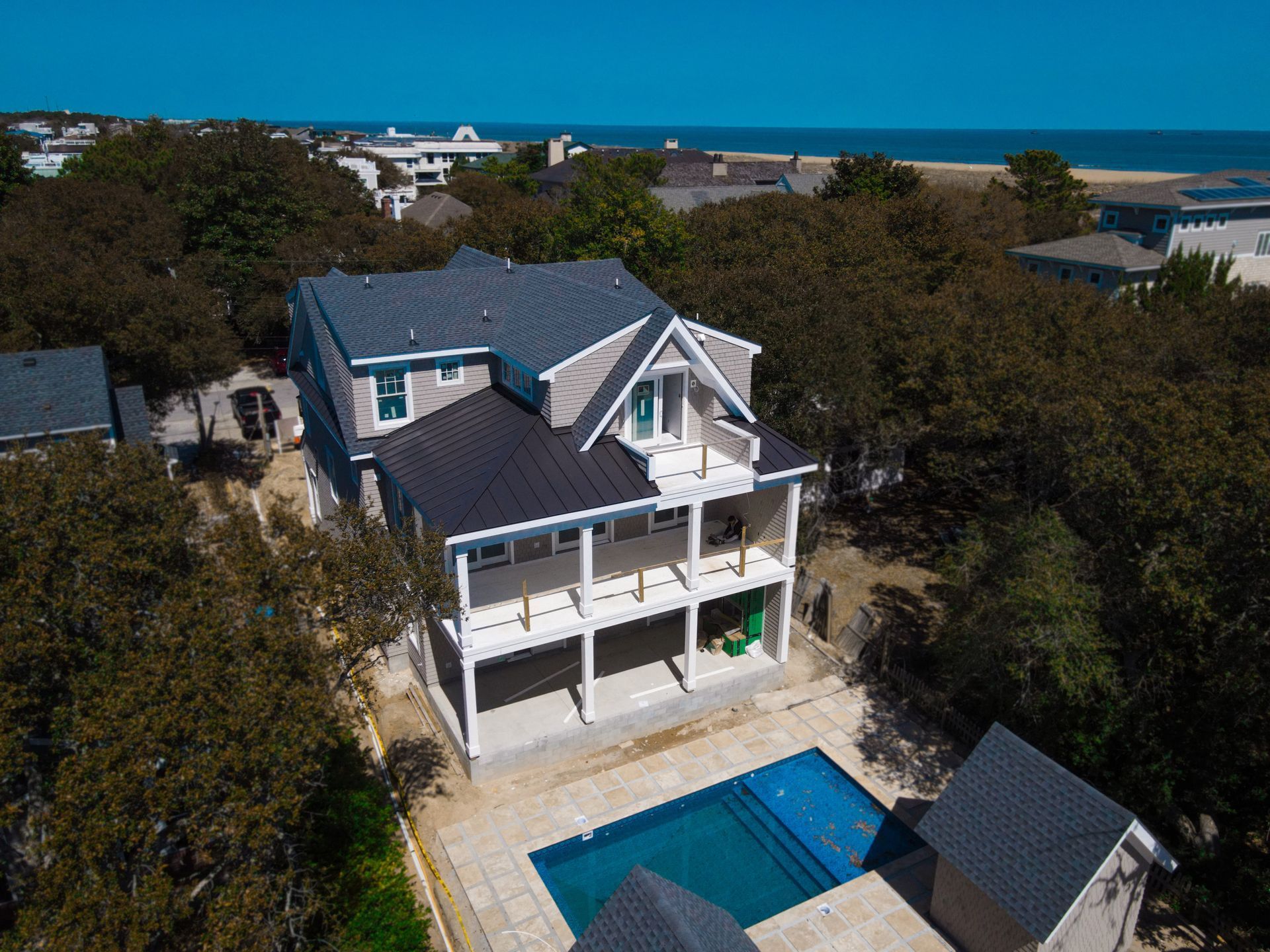 An aerial view of a house with a large swimming pool surrounded by trees.