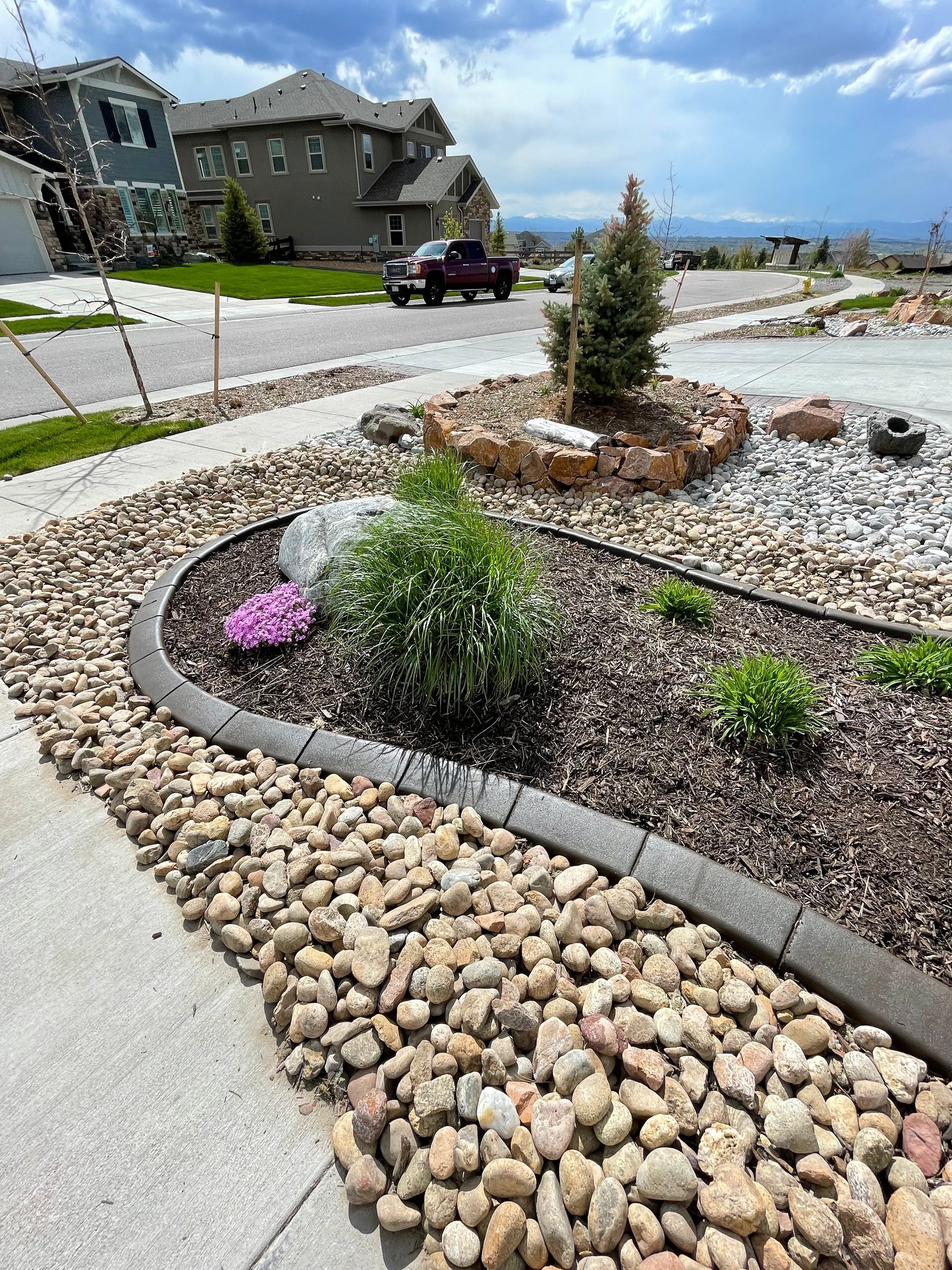 A garden filled with rocks and plants next to a sidewalk.
