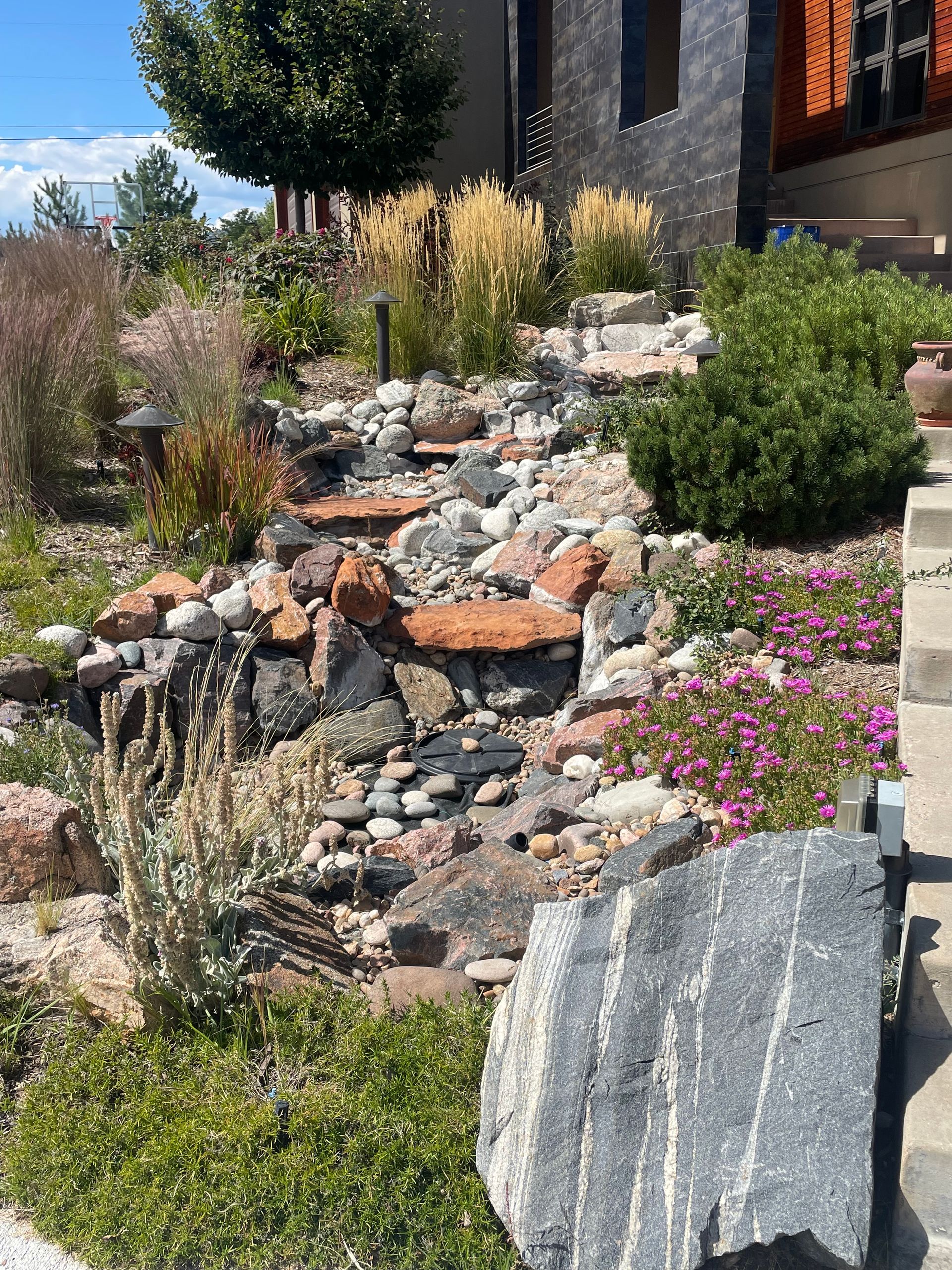 A garden with rocks and flowers in front of a house.