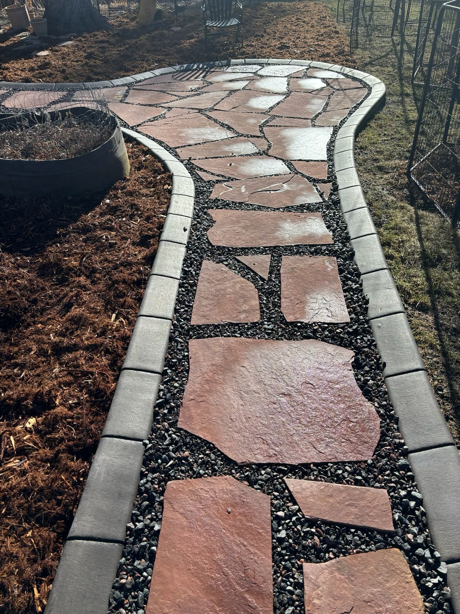 A stone walkway leading to a fire pit in a garden.
