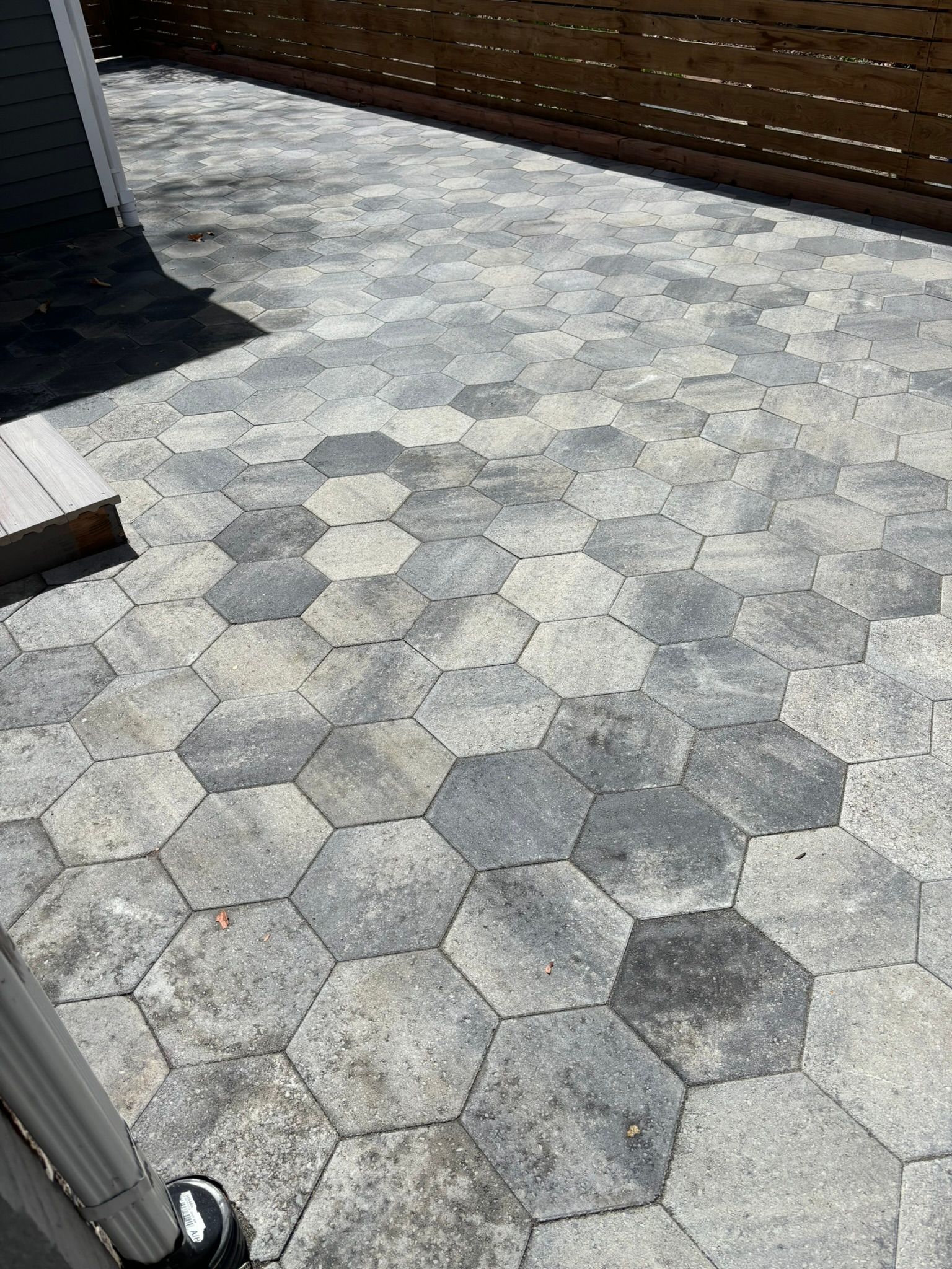 A patio with hexagonal tiles and a wooden fence in the background.