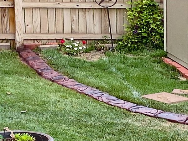 A lawn with a brick border and a wooden fence.