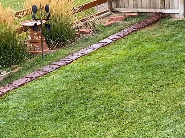 A lush green lawn with a brick walkway and a windmill in the background.