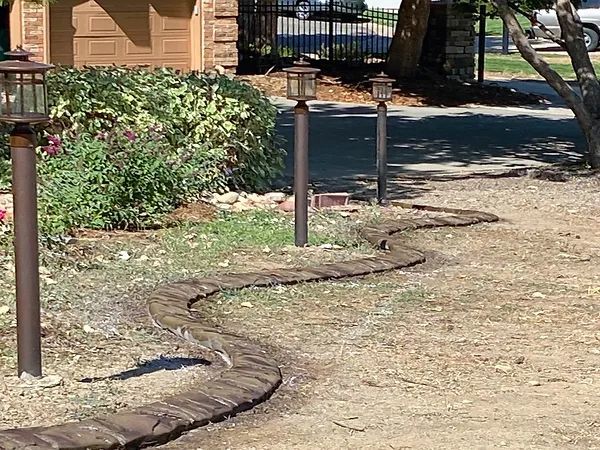 A row of lanterns are lined up in a yard in front of a house.