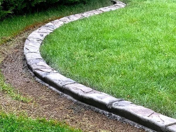 A concrete curb is surrounding a lush green lawn.