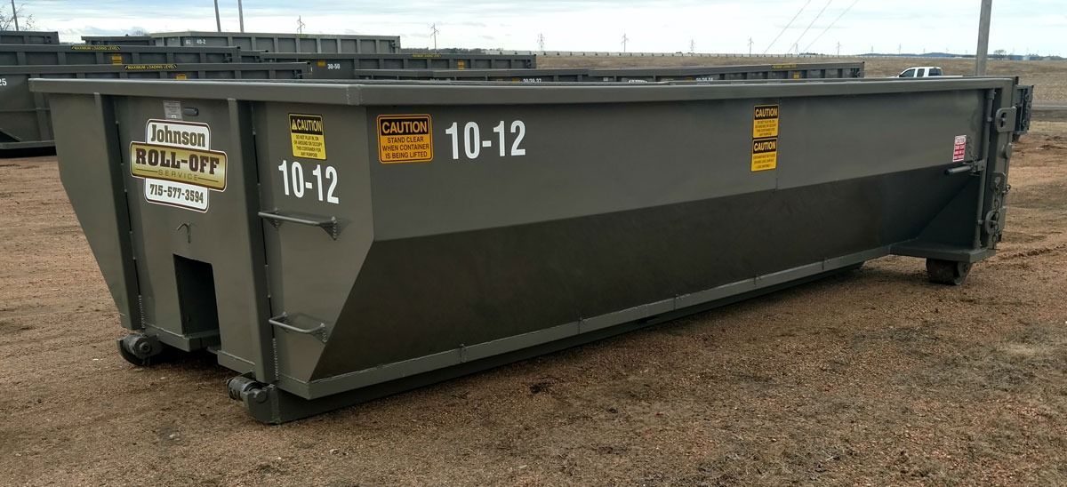 A large, olive-green metal dumpster labeled 