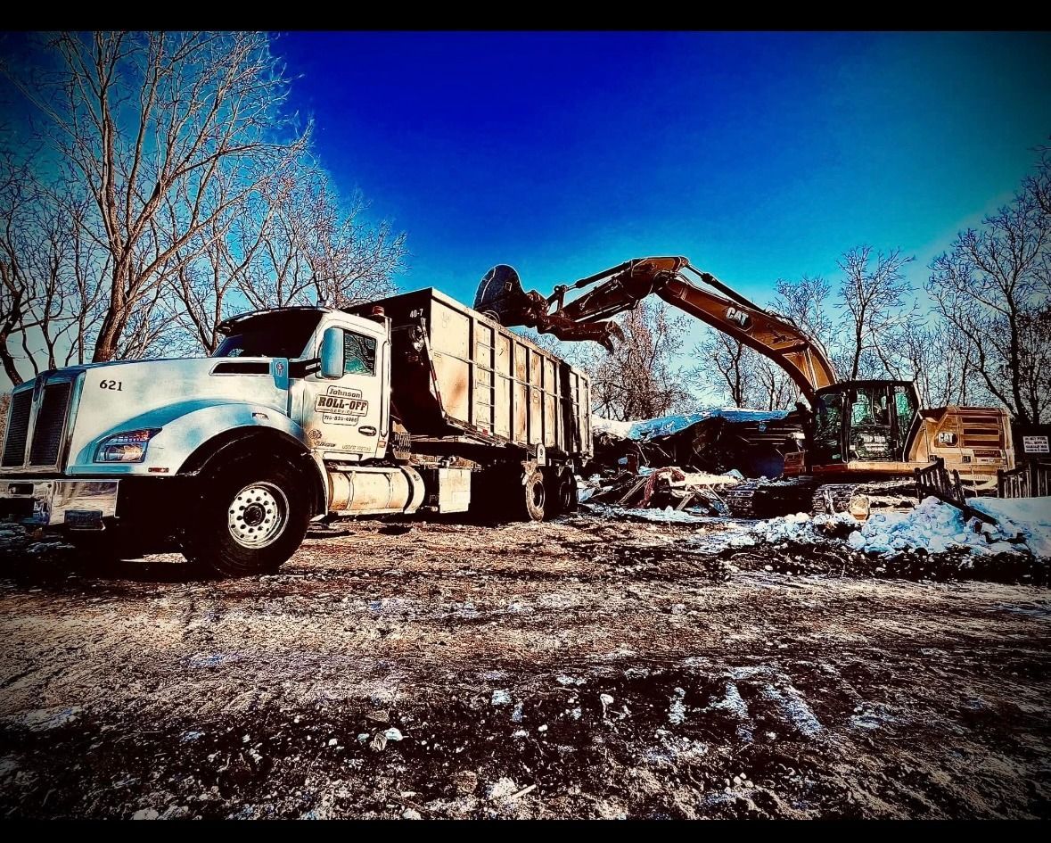 Blue dumpster being loaded with trash by a truck, outdoors.