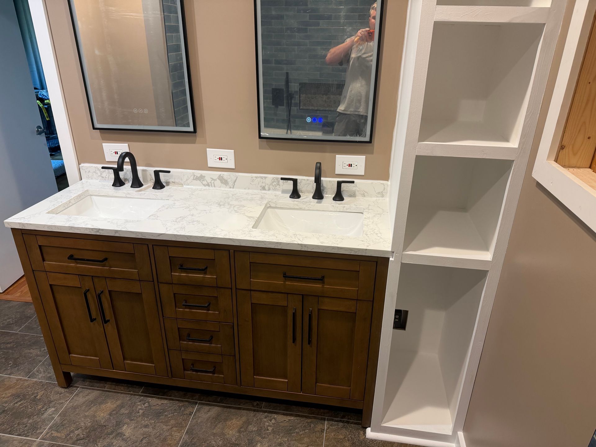 Bathroom vanity with white countertop, two mirrors, dark wood cabinets, and an open shelving unit.