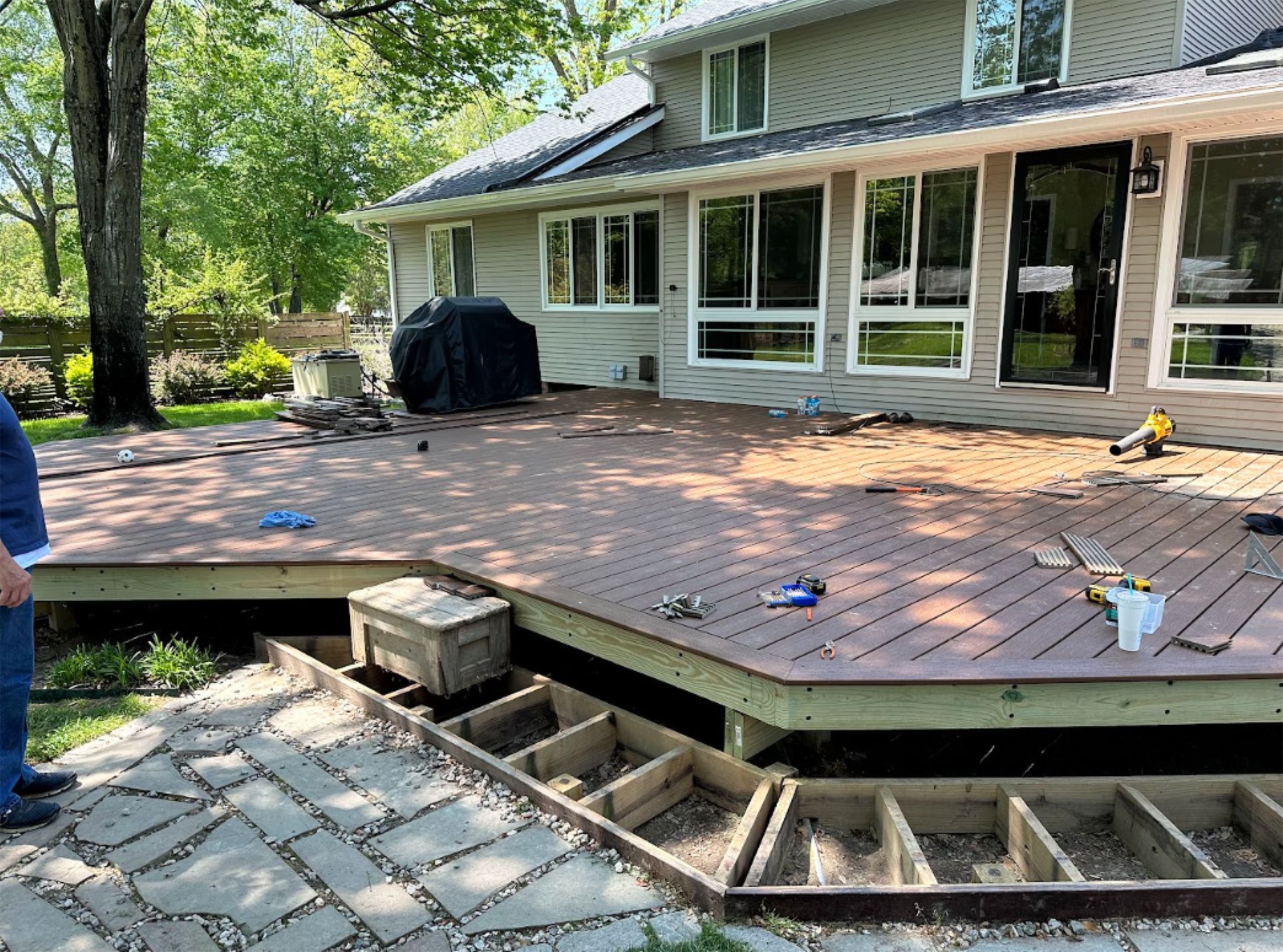 Raised backyard deck with unfinished skirting and patio furniture beside a house