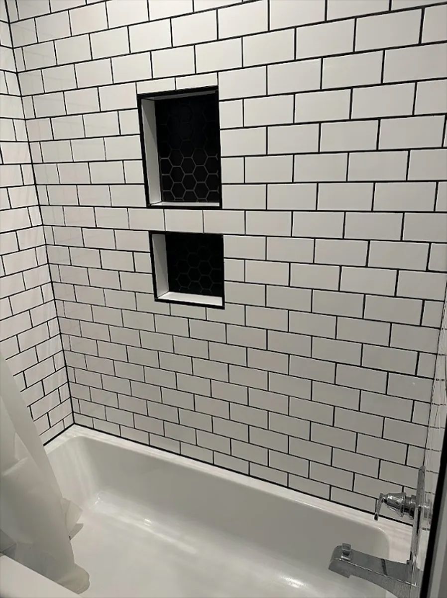 White subway-tile shower wall with two small recessed windows and a chrome shower fixture.