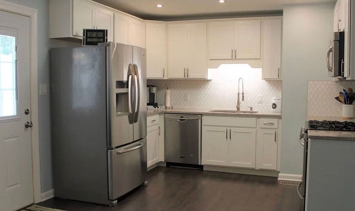 Modern kitchen with stainless steel appliances, white cabinets, and dark wood flooring