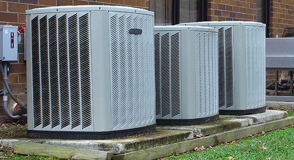 Three air conditioners are sitting on the side of a building.