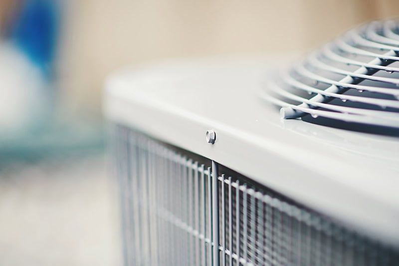 Close-up of a white air conditioner vent with blurred indoor background