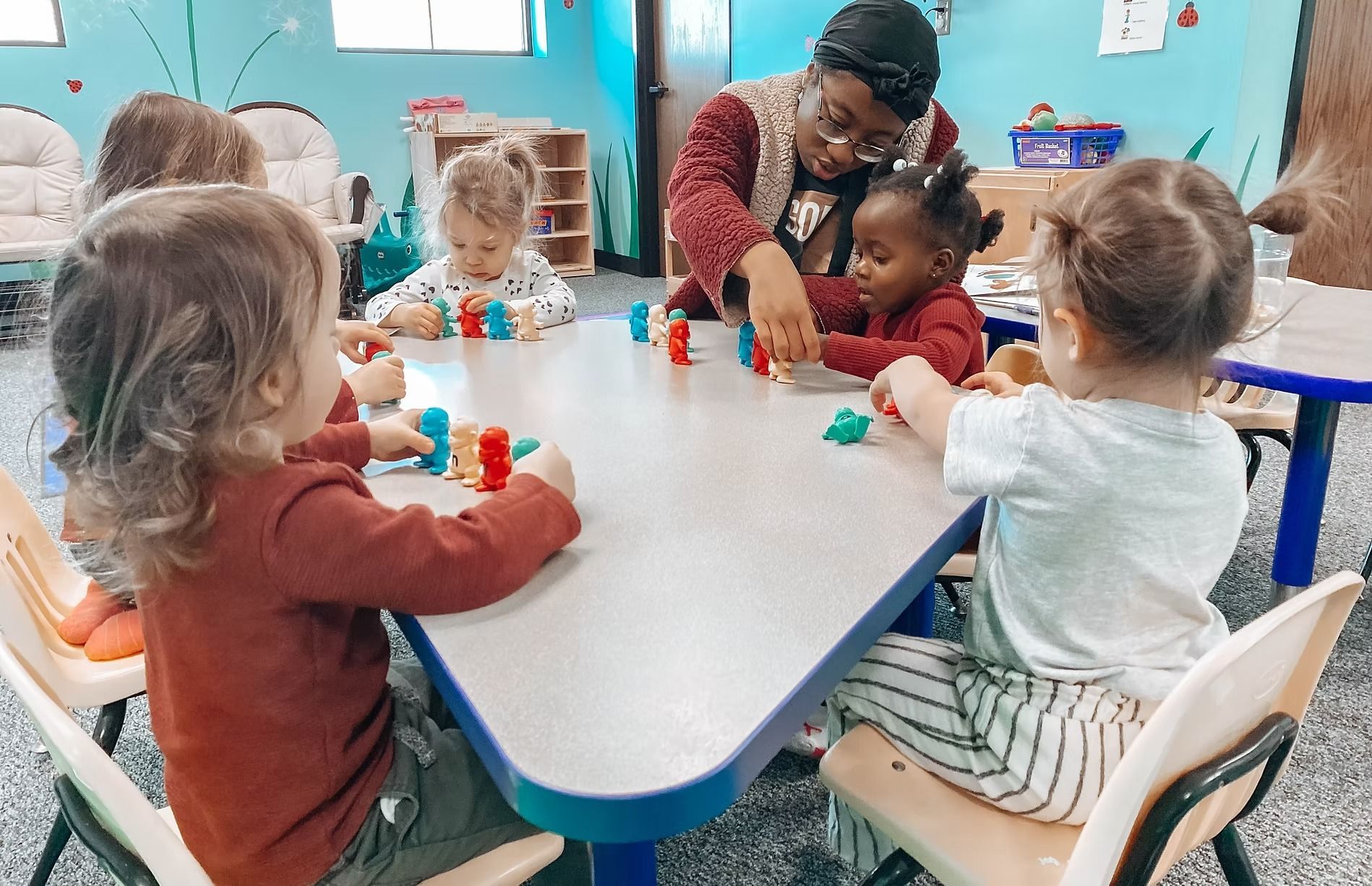 Children and teacher playing with blocks at a table in a classroom.