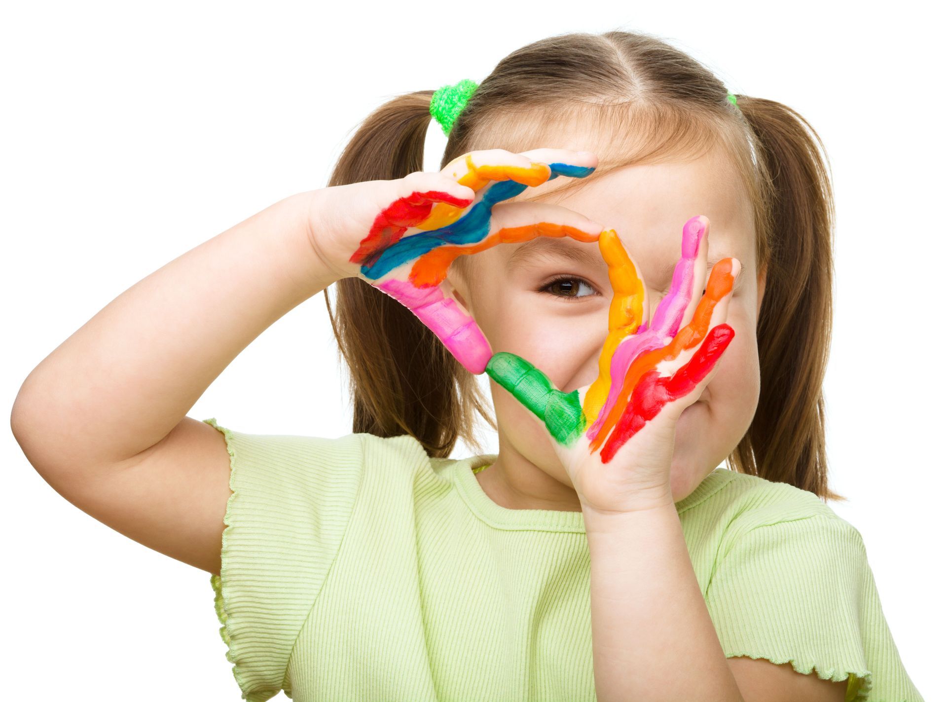Girl with pigtails holding hands up to her face, hands covered in colorful paint.