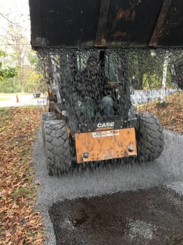 A Case loader dumping water onto a newly paved surface.