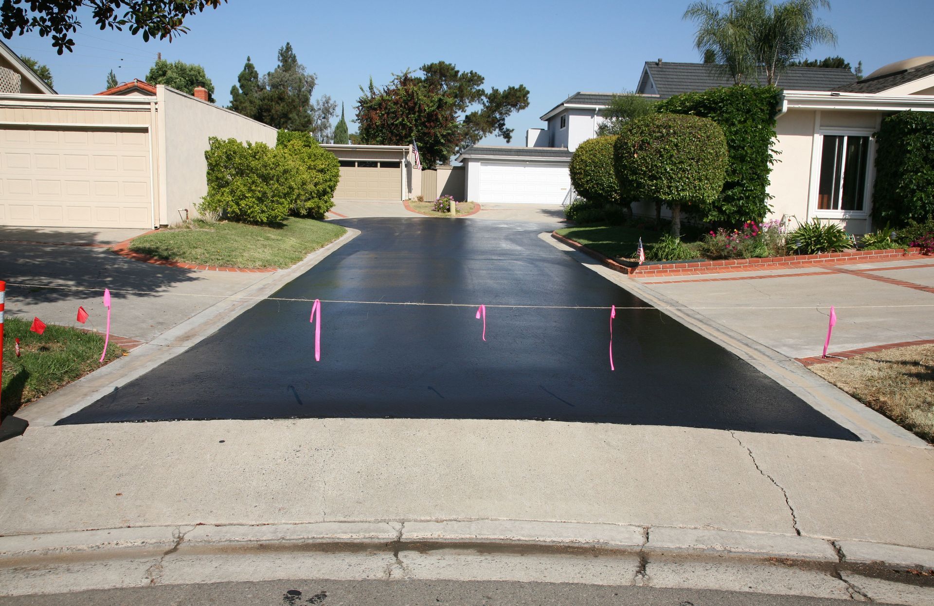 Freshly sealed asphalt driveway in front of a residential house.