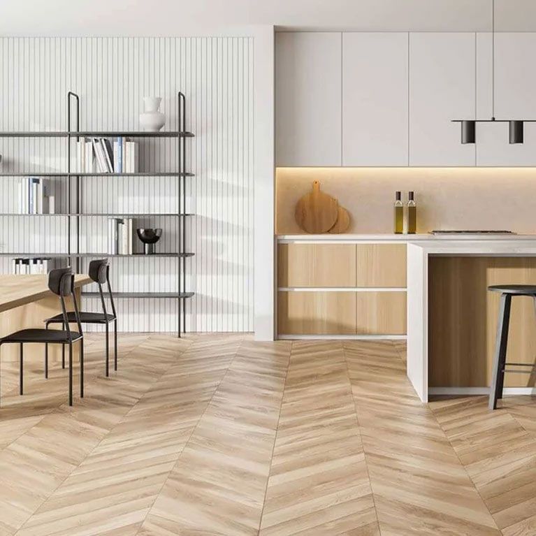 A kitchen with a wooden floor , white cabinets , a table and chairs.