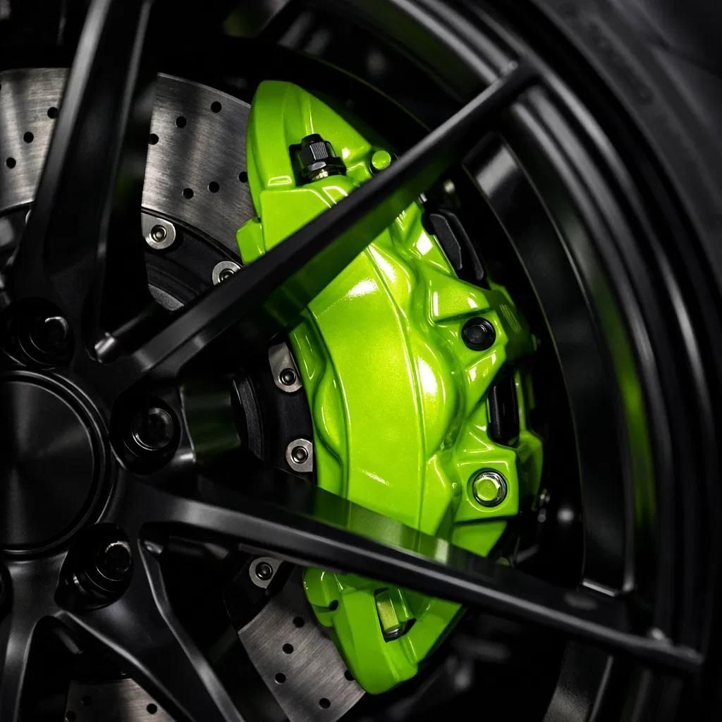 Close-up of a neon green brake caliper behind a black alloy wheel